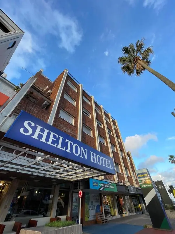 Hotel Shelton在埃斯特角城的外观,可见蓝色招牌和一棵棕榈树